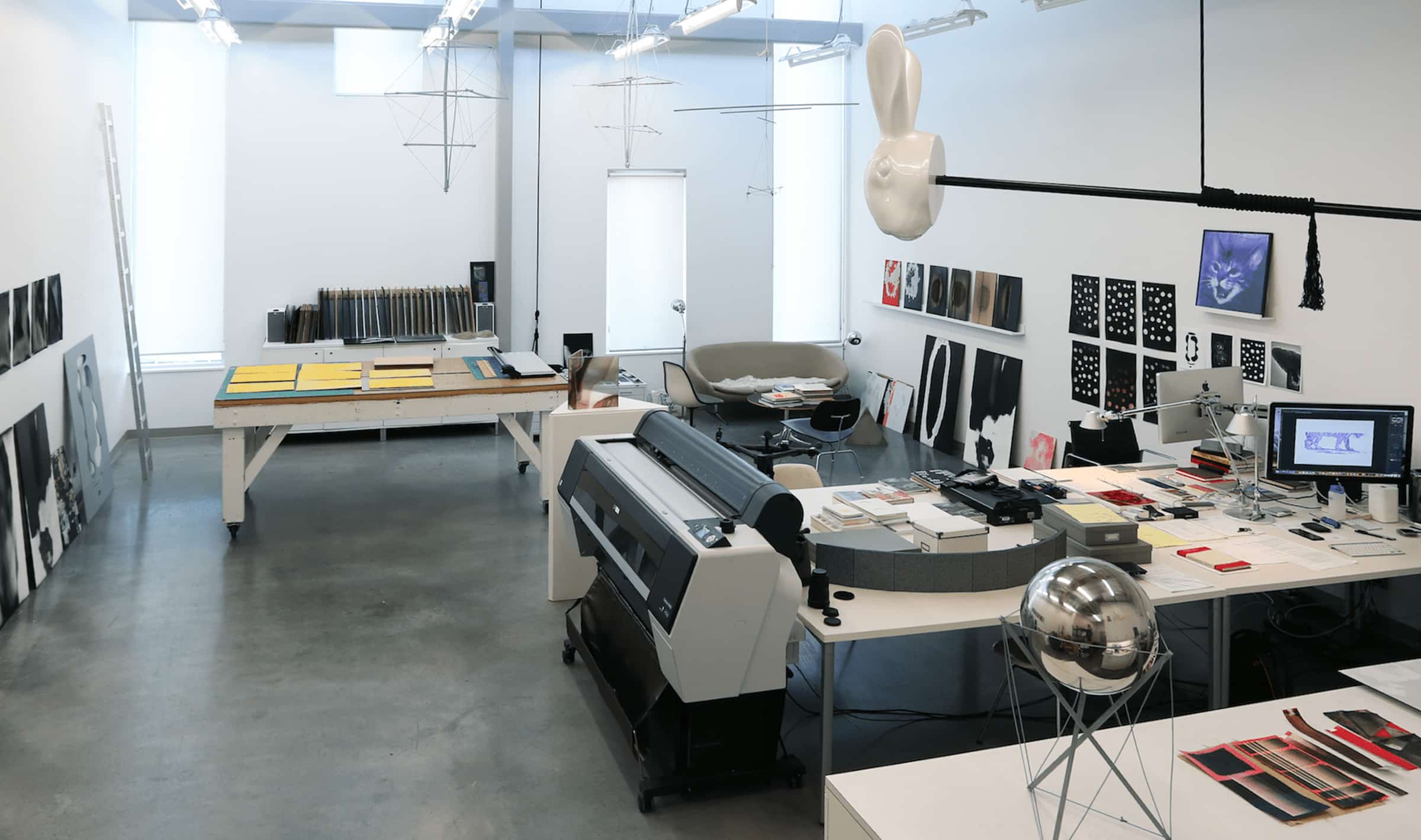 The Studio for Extensive Aesthetics (SEA) at Emily Carr University of Art + Design is a vibrant and creative workspace dedicated to exploring the intersection of art, design, and technology. The studio features modern equipment such as large-format printers, computers, and workstations, alongside artistic installations like hanging sculptures and wall-mounted artworks. This environment supports transdisciplinary research, fostering collaboration between students, faculty, and international experts on experimental data collection, interpretation, and installations.