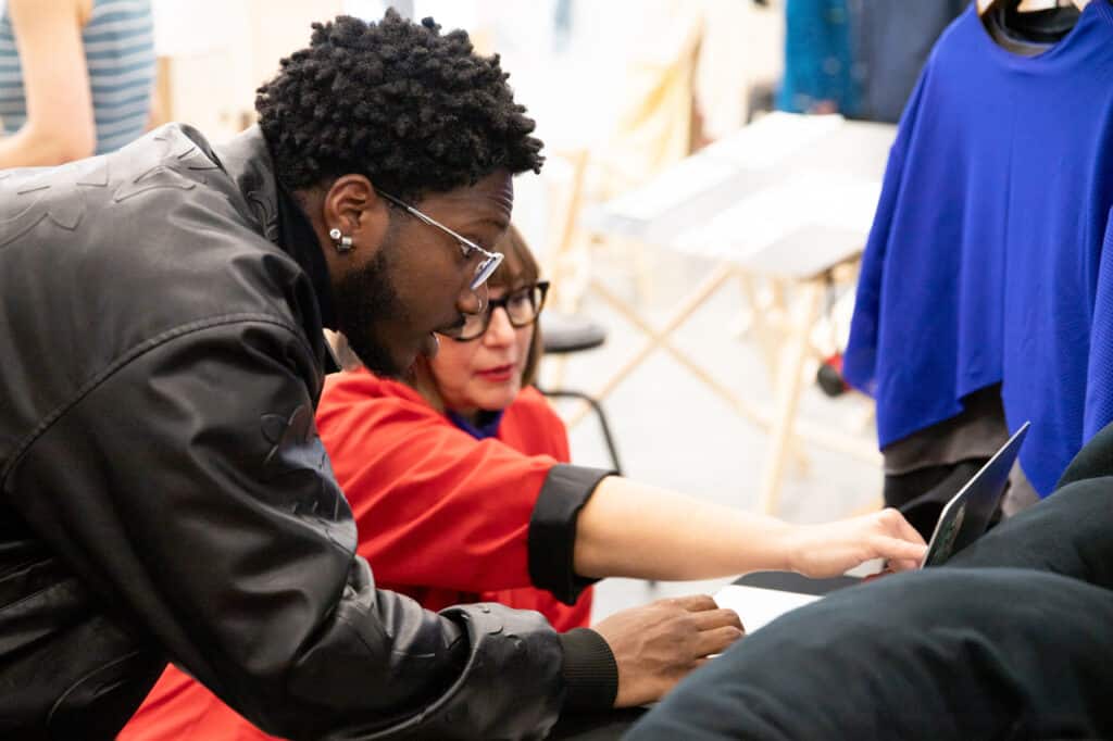 Two people looking at a laptop together, with one pointing at the screen and the other leaning in to see.