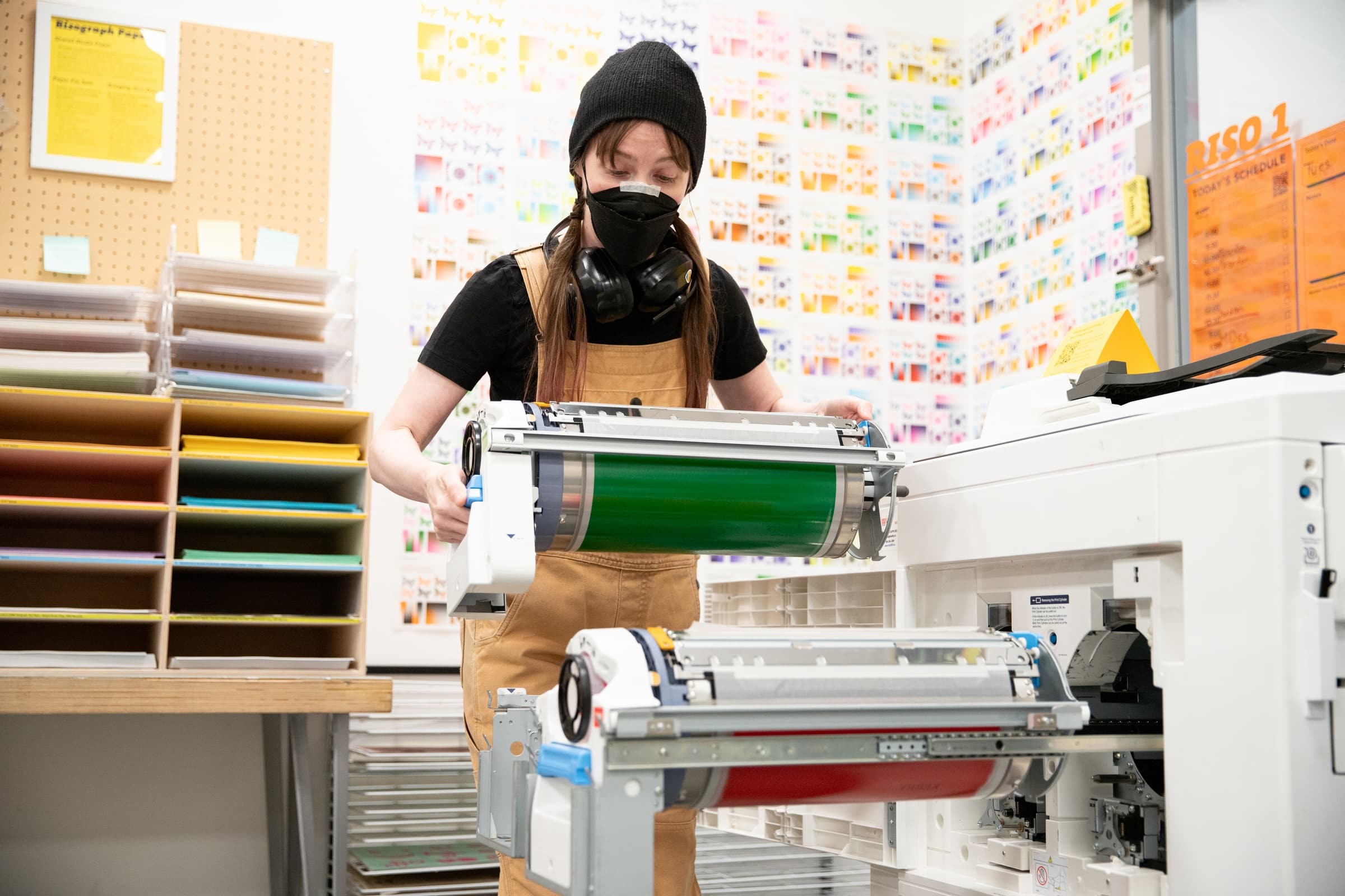 Technician Kathleen Jacques loading an ink drum on Risograph printer.