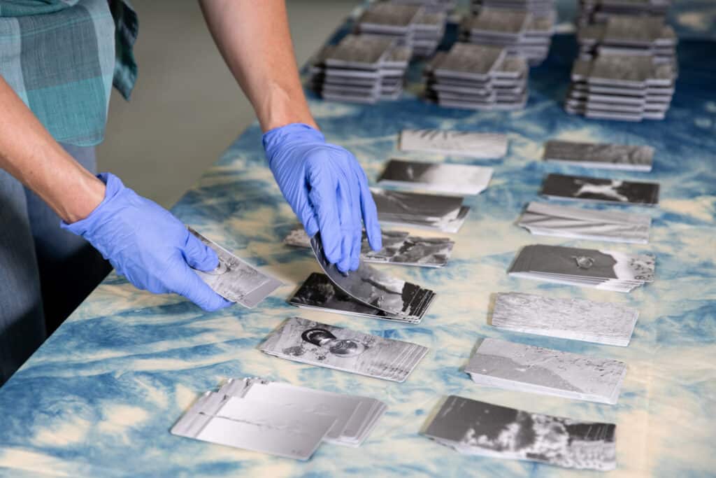 Hands in blue plastic gloves, rearranging photos on a table