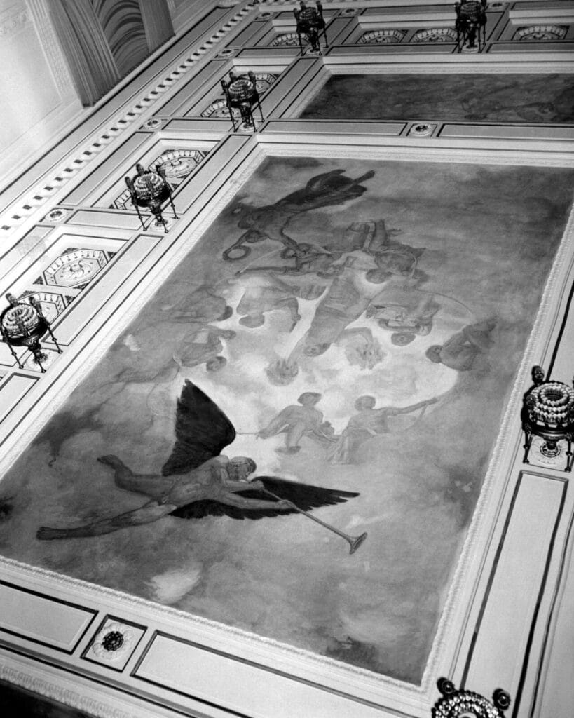 A ceiling mural depicting winged figures in flight, framed by ornate architectural details and lamps.
