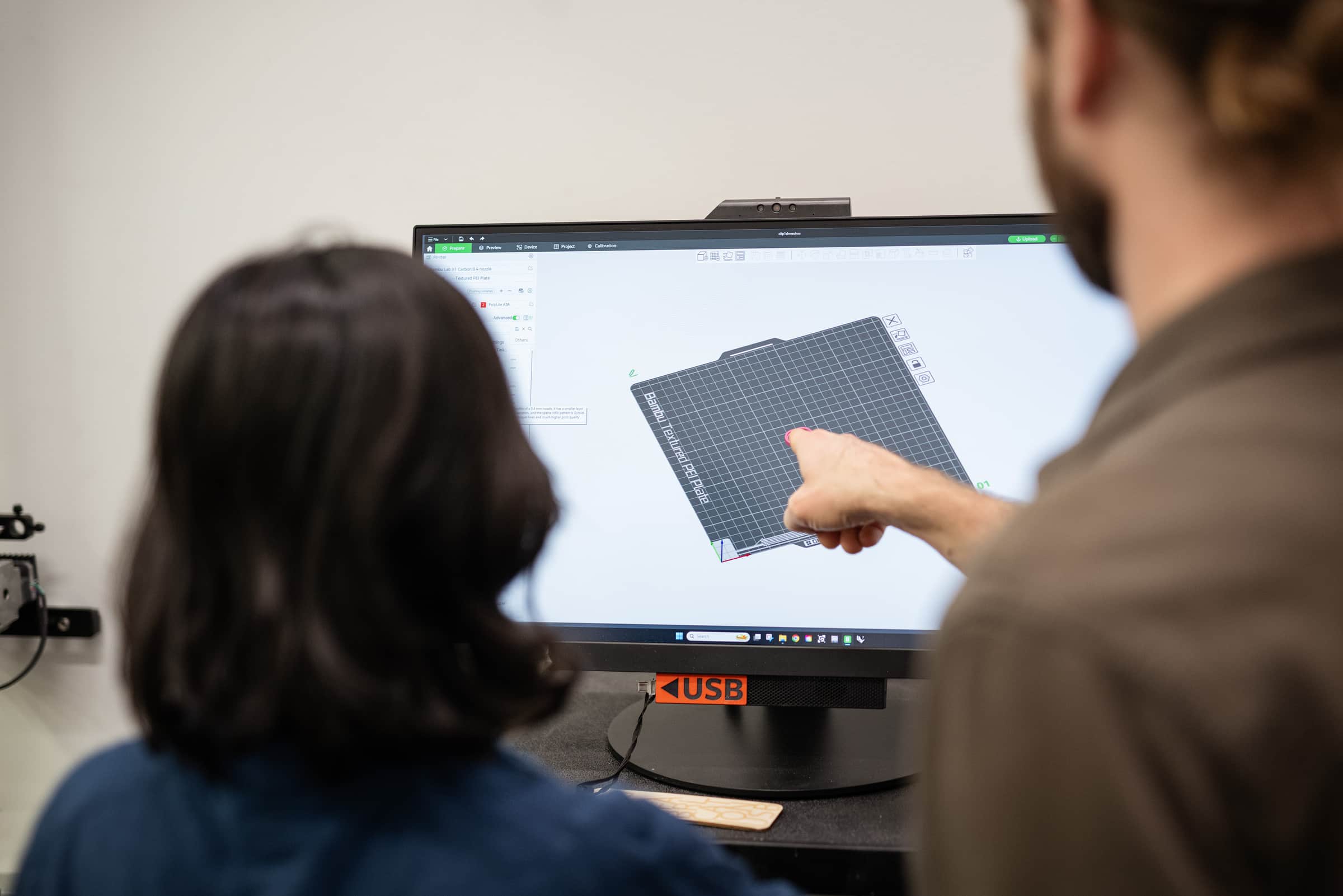 Student and technician reviewing a 3D model file on a computer screen.
