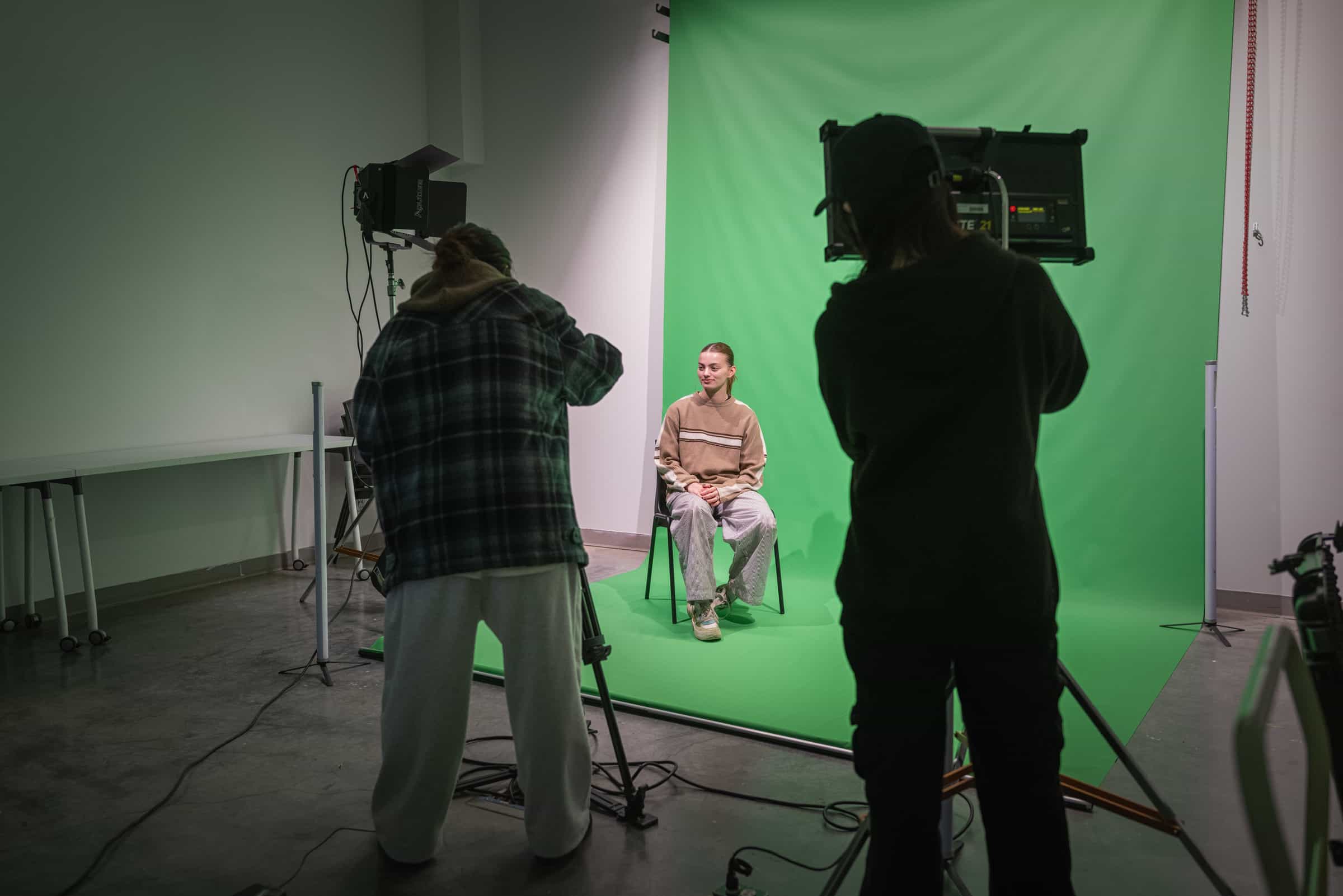 Students shooting in front of a green screen.