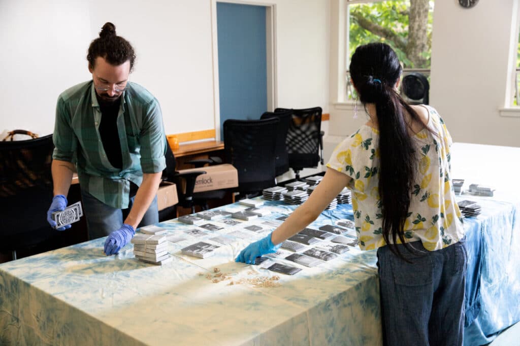 Two people wearing gloves organize stacks of photographic tarot cards on a large table.