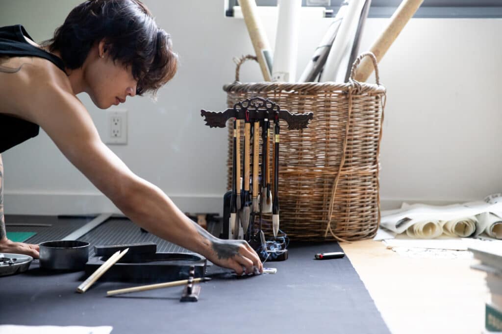 Person reaching across the floor toward brushes arranged in a stand.