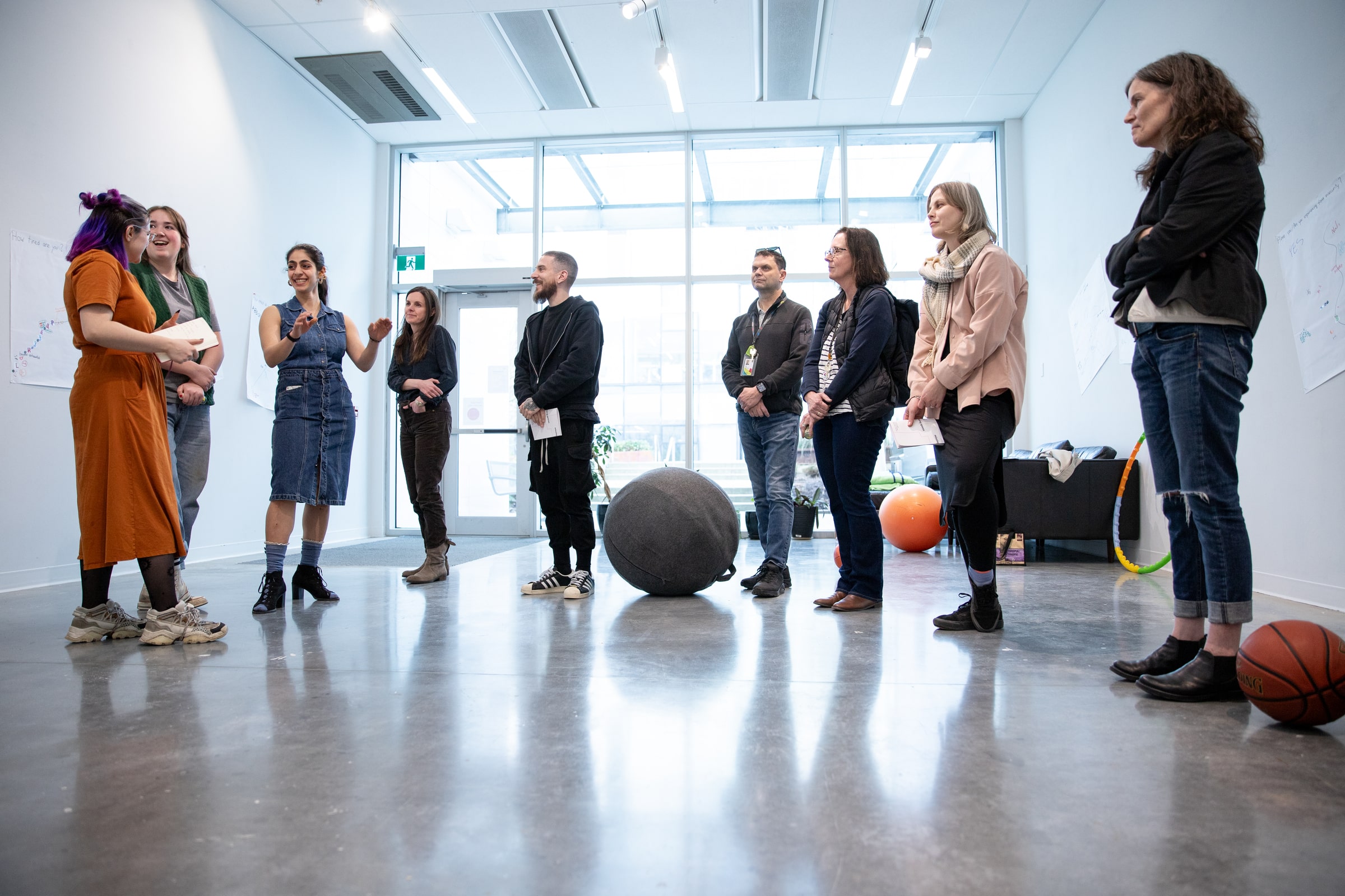 Group of students and faculty stand in a circle in a gallery space, engaged in conversation during a critique or curatorial presentation.
