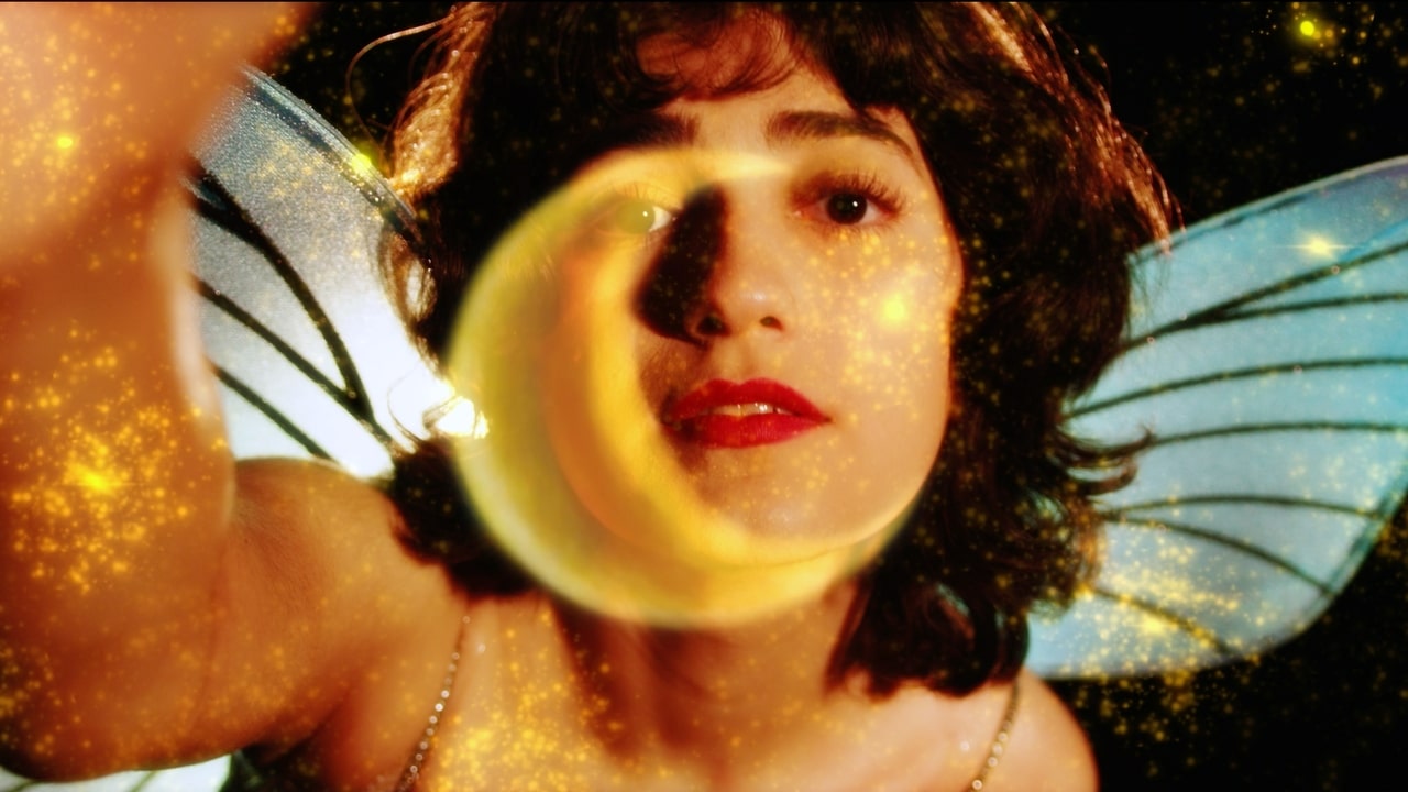A transparent moon partially obscures a woman with red lipstick and brown hair and wings.