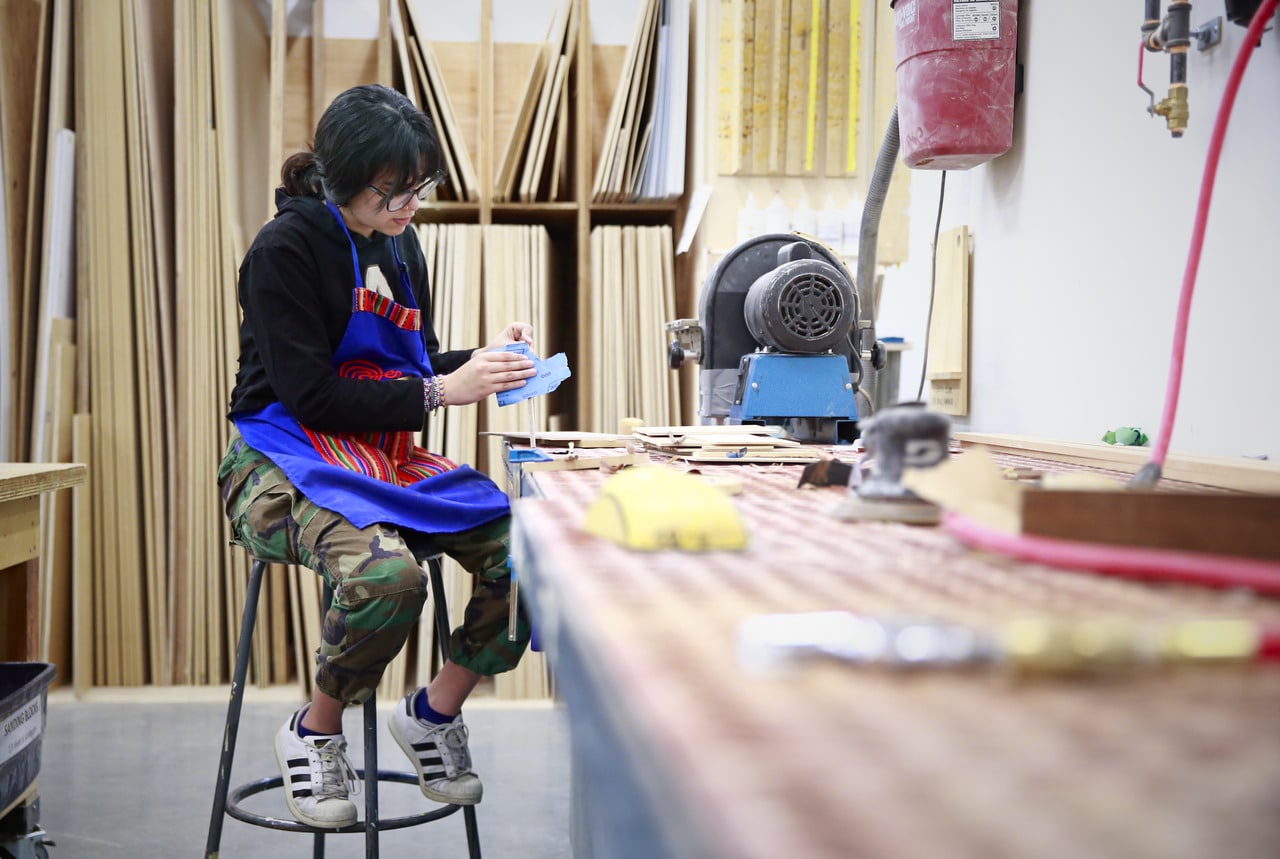 Student sanding a wood piece in the Design Wood Shop.