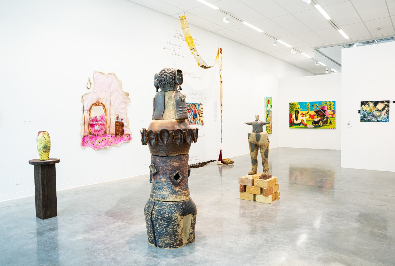 We see 3 large sculptures in the middle of the exhibition spaces, with paintings on the walls around them. All the pieces are colourful and whimsical.