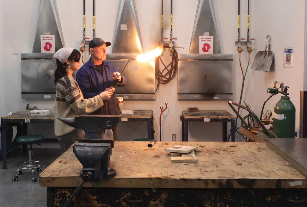 Instructor demonstrates torch work to a student in ECU’s metal shop.