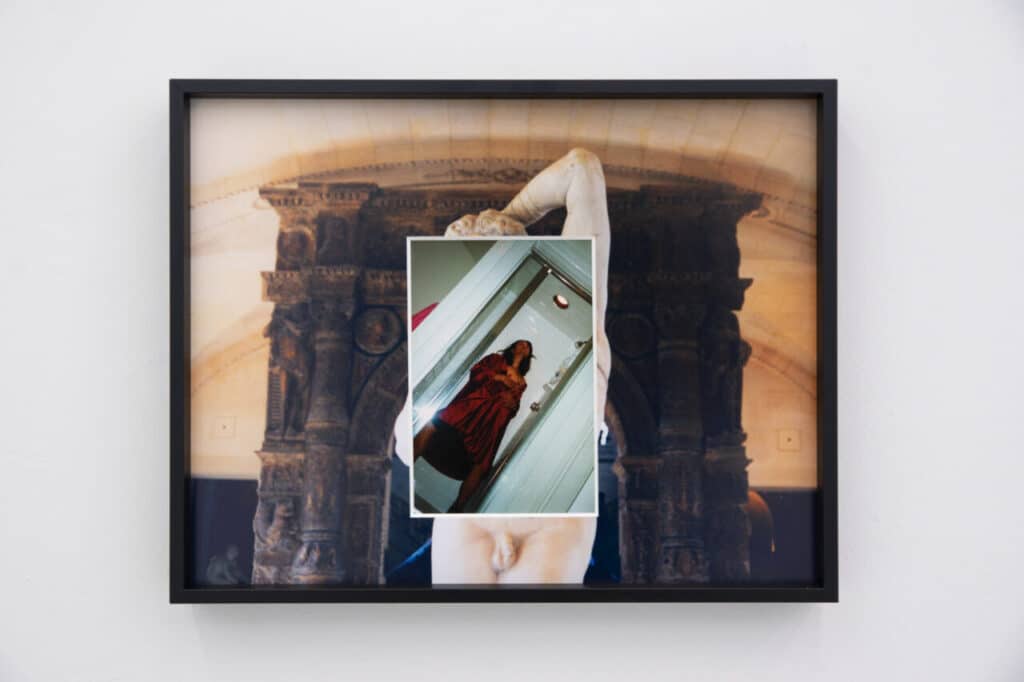 Framed artwork showing a photograph of a person in a red robe standing in a doorway, placed over a background image of a large classical sculpture.
