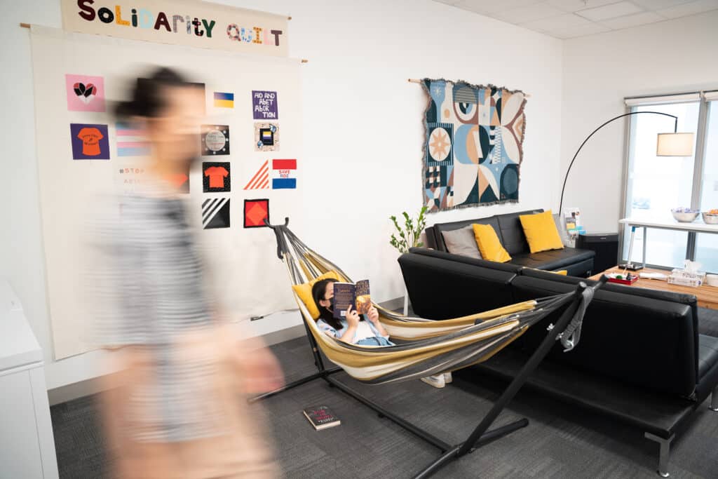 Student reads in a hammock inside a cozy lounge with a “Solidarity Quilt” display.