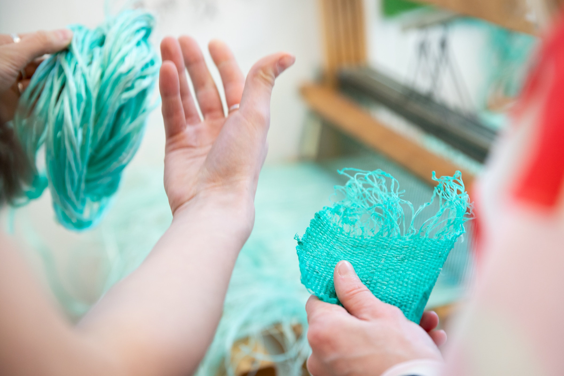 Close-up of a vibrant abstract artwork made from layers of rolled felt in swirling patterns of red, orange, green, purple, yellow, and pink.