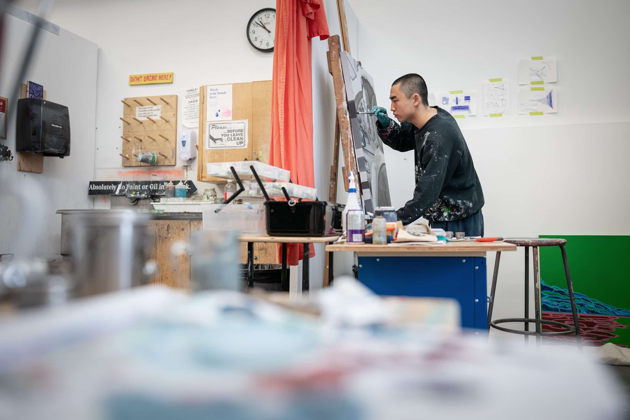 Student leaning over a painting propped up on an easel in the painting studios.