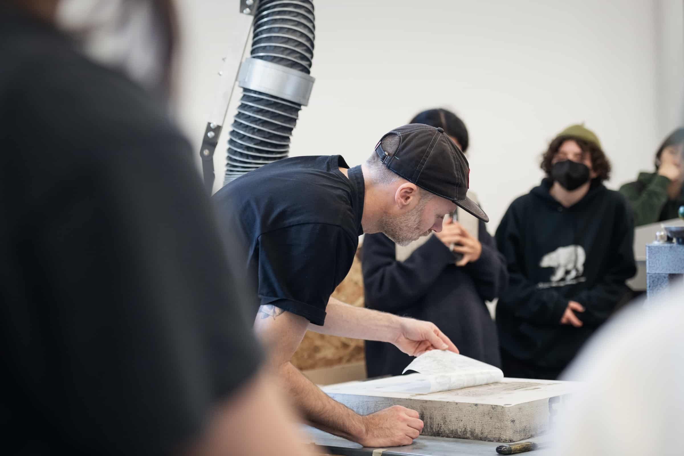 Faculty member peeling paper off of a stone for a lithography demonstration.