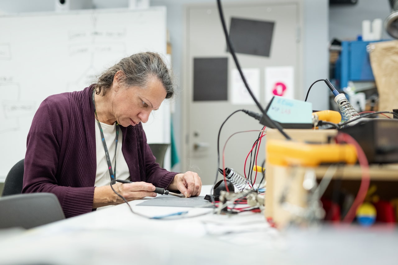 Technician soldering at a work table in the WIP Lab.