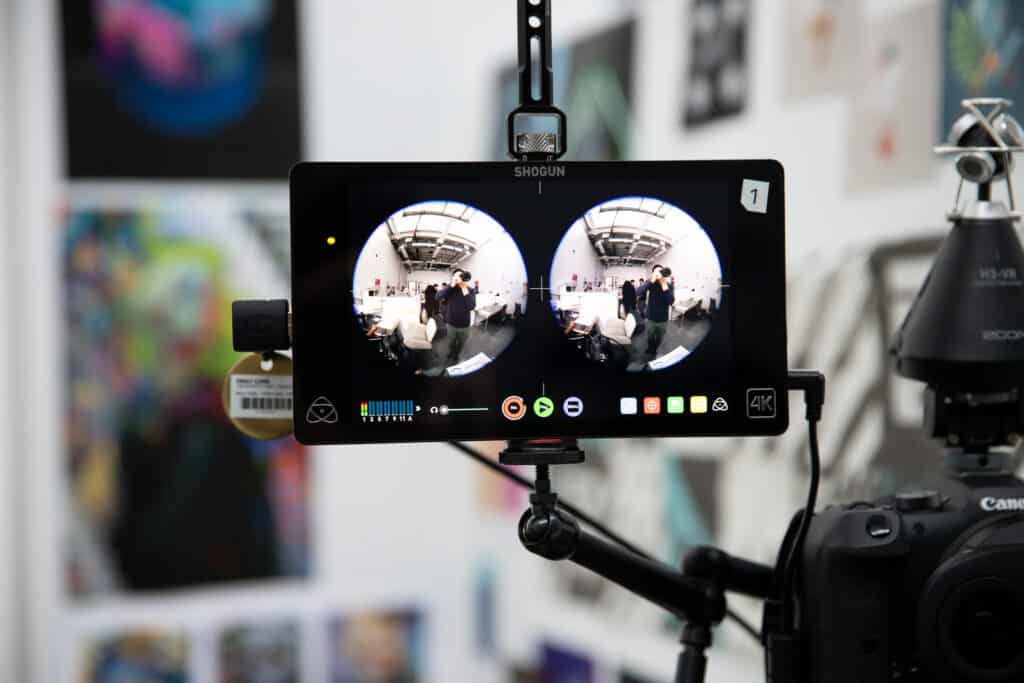 Close-up of a camera monitor displaying dual fisheye lens footage of a studio space, part of a setup for immersive video recording.