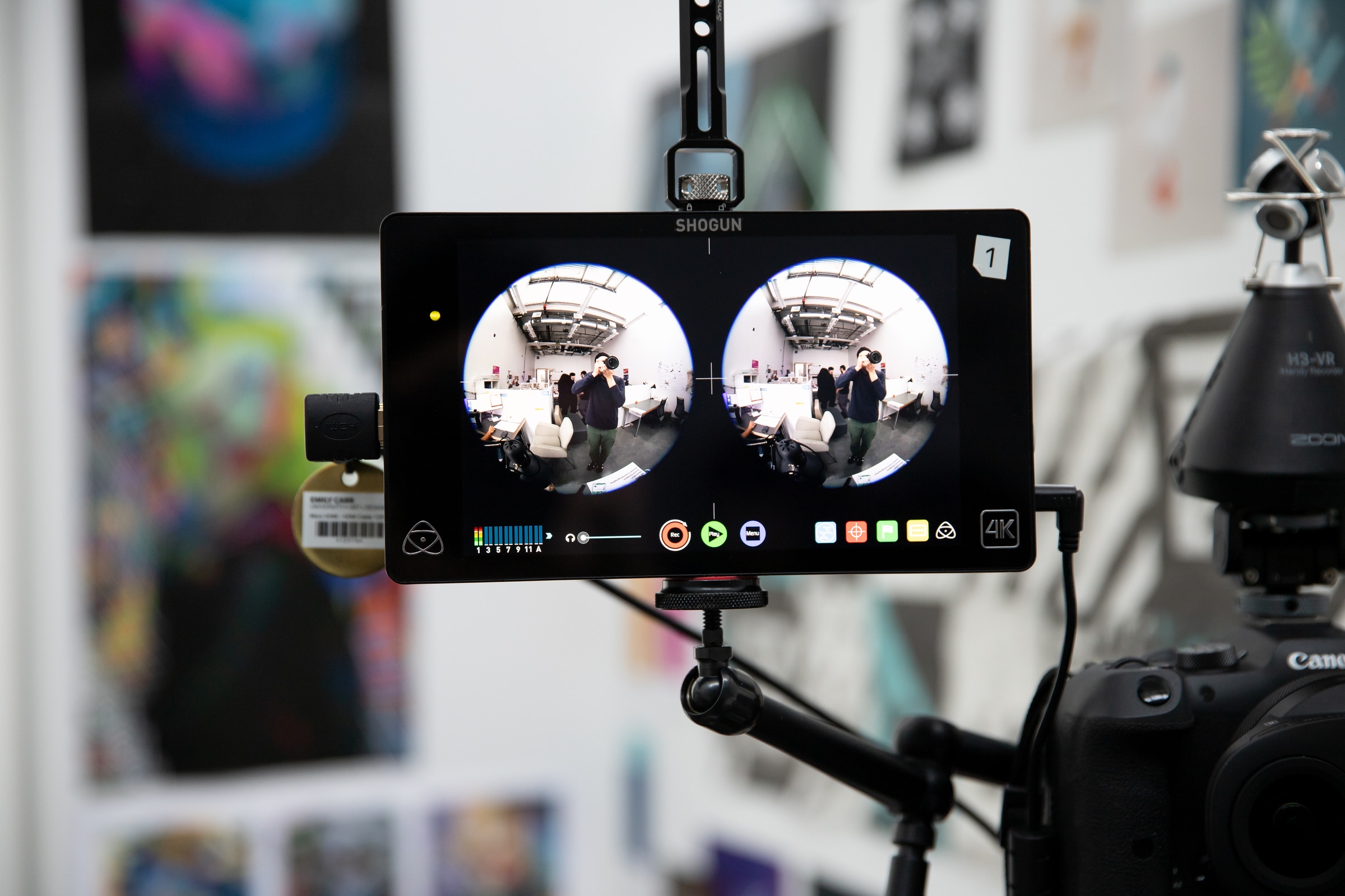 Close-up of a camera monitor displaying dual fisheye lens footage of a studio space, part of a setup for immersive video recording.