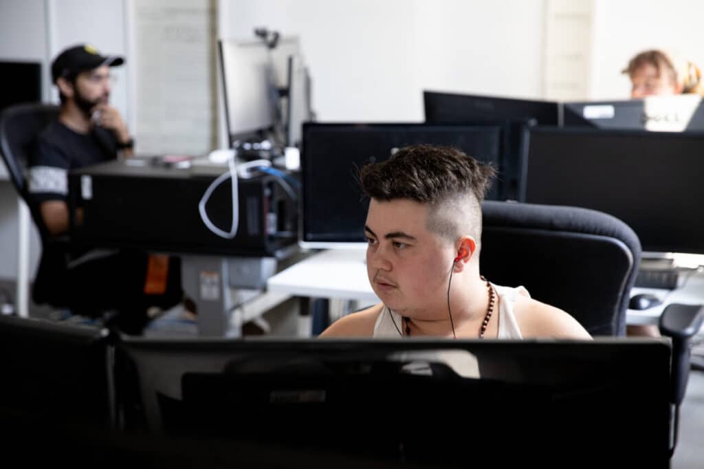 A person wearing headphones focusing on a computer screen in an office.