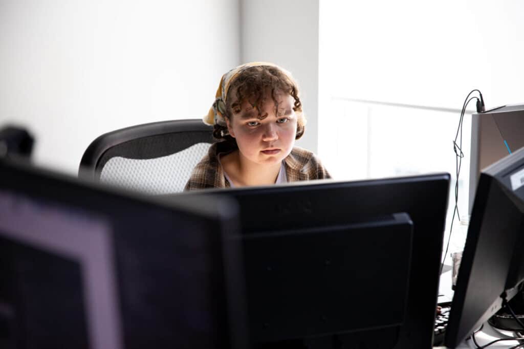 A person sitting at a desk, looking at a monitor with concentration.