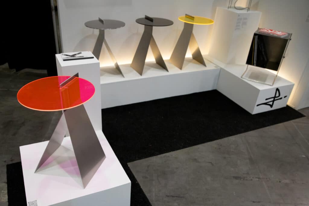 A display of modern tables with metal bases and colourful acrylic tops in red, black and yellow.