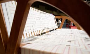 A wooden bench with an interwoven patterned seat, photographed through the frame.