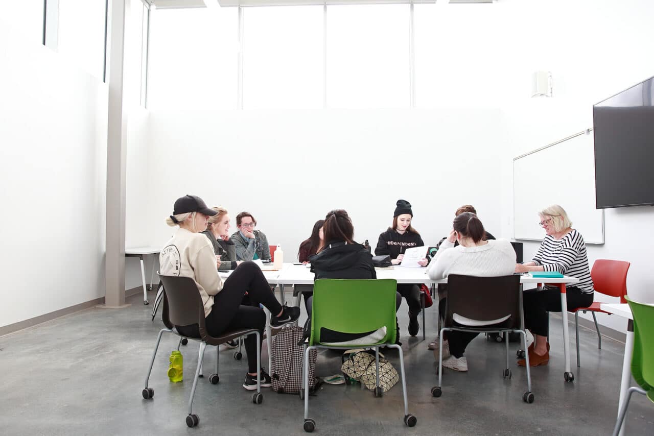 A group of people sitting at a white table working together.