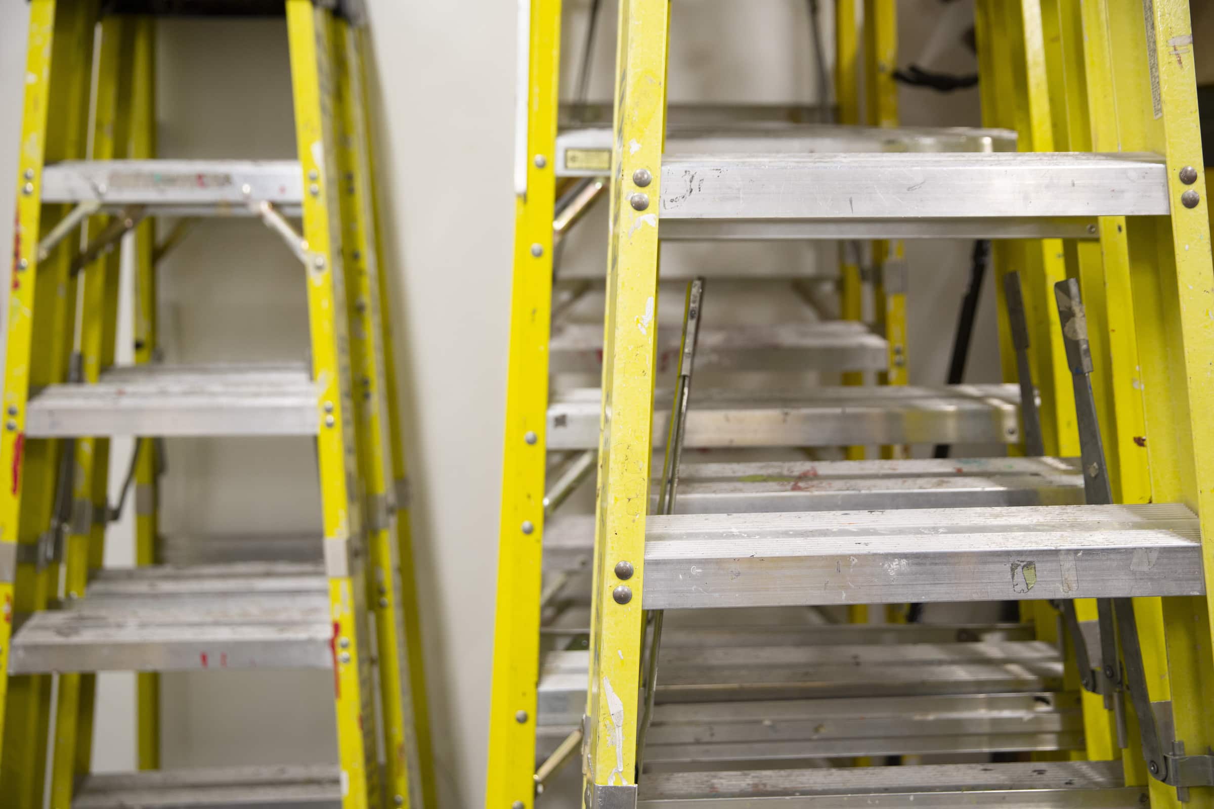 Yellow ladders stacked against a wall.