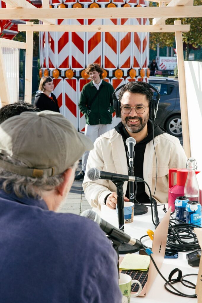 Close-up of two people talking into microphones during a discussion inside a wooden pavilion.
