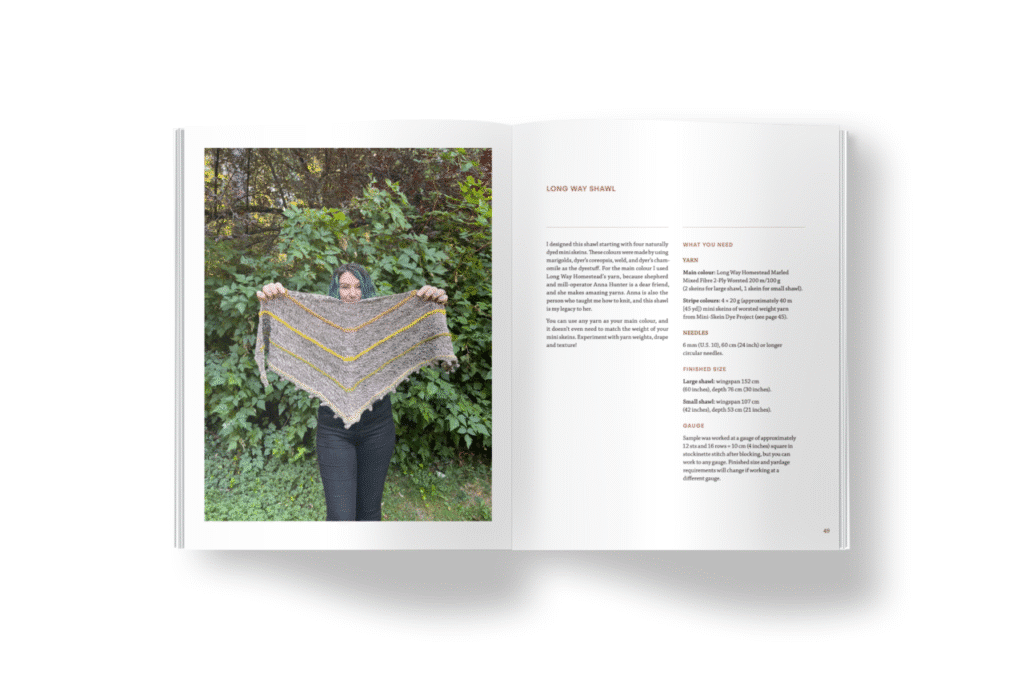 An open book spread showing a person standing outdoors holding up a handmade triangular shawl with yellow and grey stripes. The facing page includes knitting instructions and materials for making the shawl.