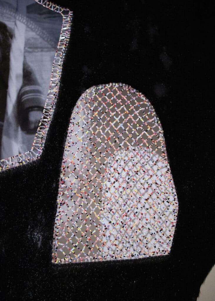 A close-up of a mixed-media textile piece featuring beadwork in a diamond pattern stitched over a dark fabric background.