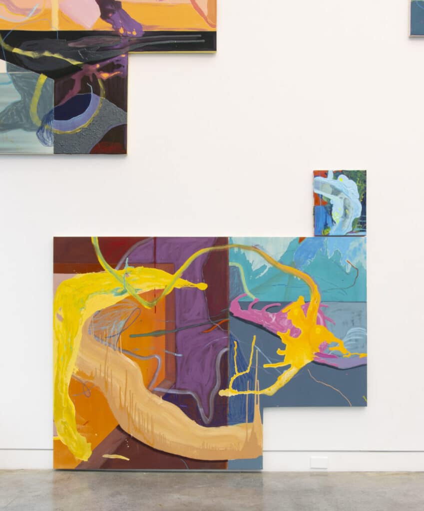 A set of abstract paintings composed of bold brushstrokes and layered forms in bright colours including yellow, orange, purple, and blue. The canvases are arranged asymmetrically on a white gallery wall, creating a dynamic visual rhythm.