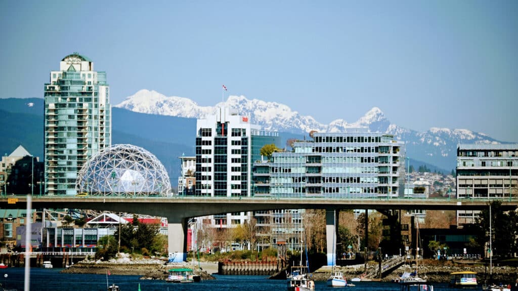 Science World dome with the North Shore mountains behind it, seen across False Creek with boats in the foreground.