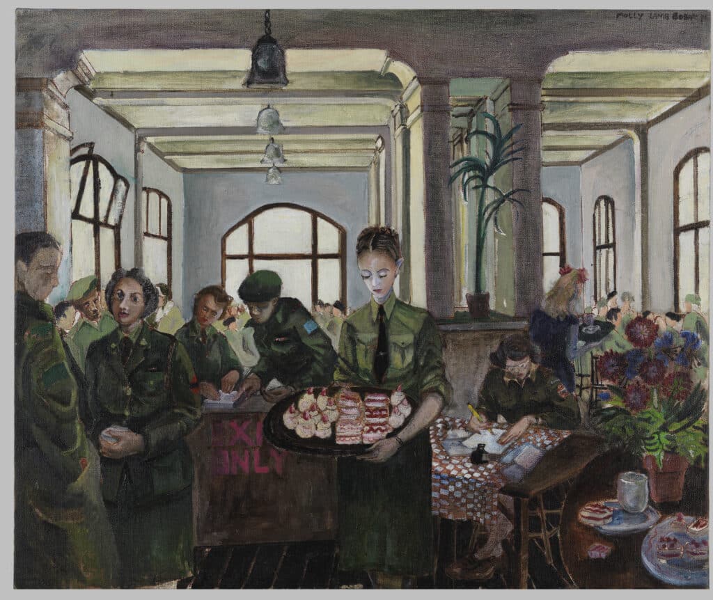 Women in uniform serve cakes and work at tables in a bright canteen filled with soldiers and large windows.