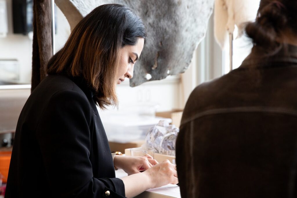 A participant concentrating on arranging handmade samples at a studio table, surrounded by natural fibres, papers and sculptural textures.