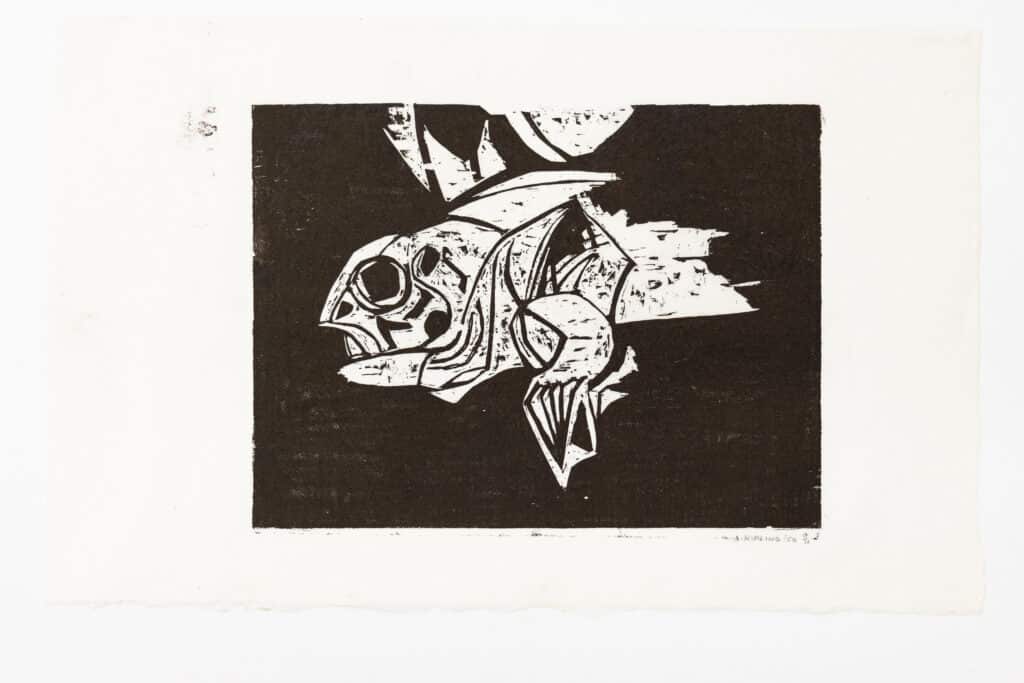 A print of an abstract figure resembling a fish made with dark black ink on white paper.