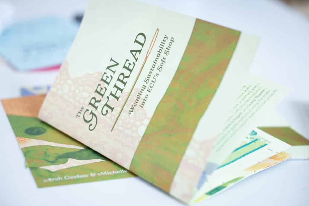 A printed booklet with green graphics and fonts sits partially open on a grey table.
