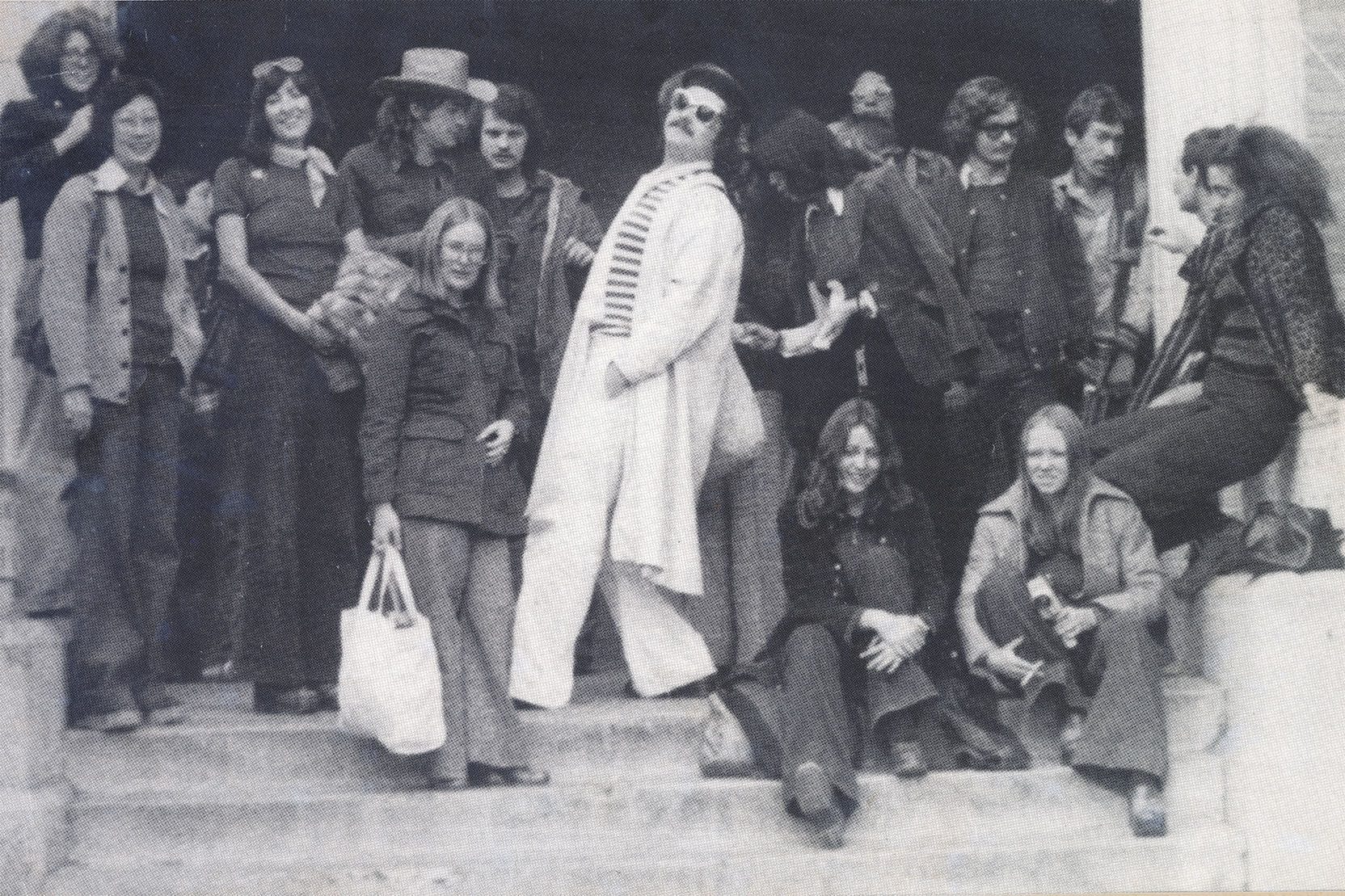 A group of fashionable students socializing on the front steps of the school in the 1970s.