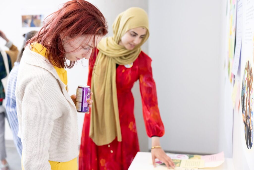 Two people lean over a desk to explore printed materials.