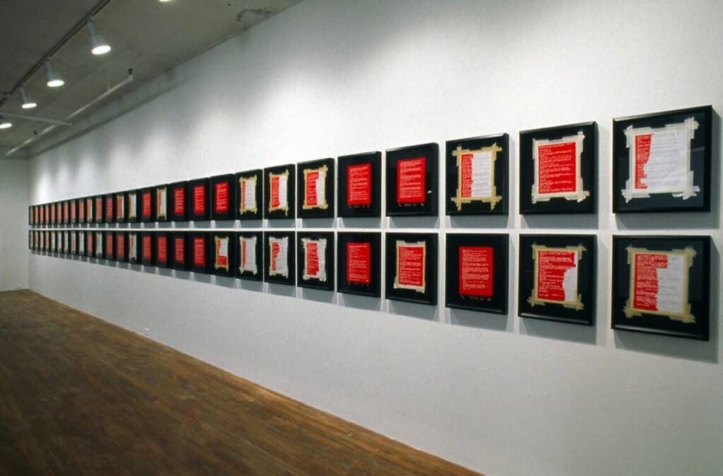 Gallery wall displaying a long row of framed works with red and white beaded elements.