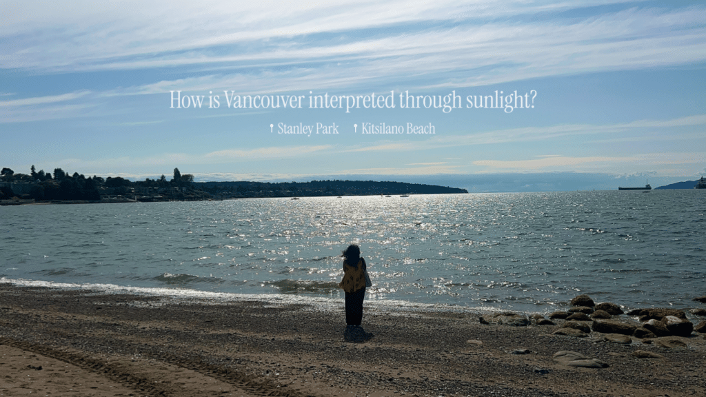 A person stands on a sunblasted shoreline at the edge of a sparkling ocean under a blue sky with freighters and mountains in the distance under white text which reads, "How is Vancouver interpreted through sunlight?"