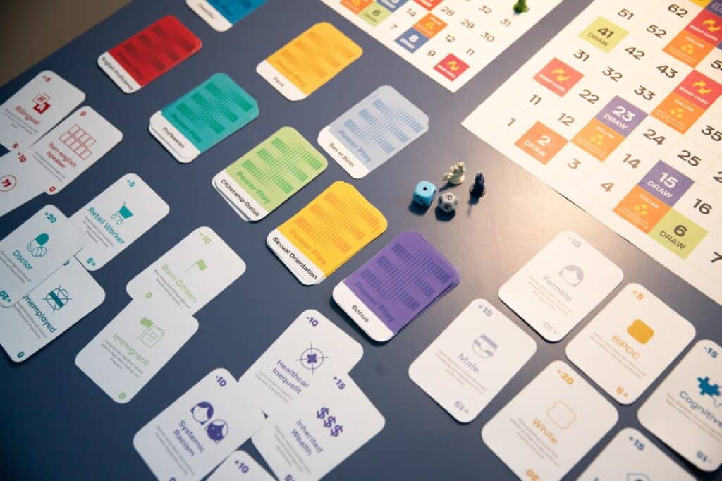 A series of colourful cards, dice and figurines sit on a dark table under lamplight.