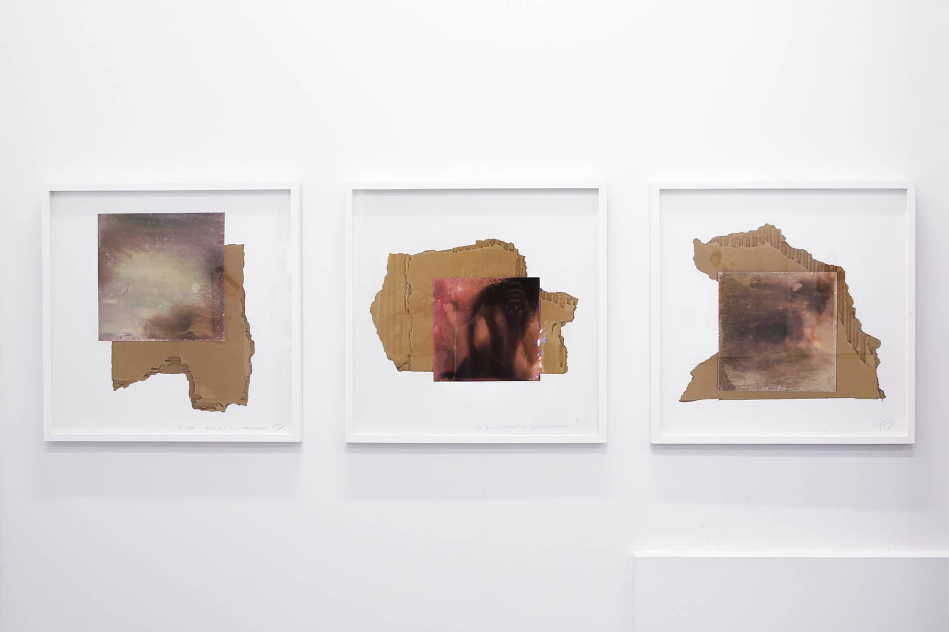 Three framed mixed-media artworks displayed side by side on a white wall, each combining torn cardboard forms with layered photographic images.