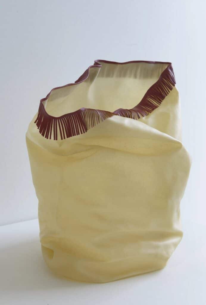 Soft, translucent sculptural form with a folded surface and dark red fringe along the top edge.