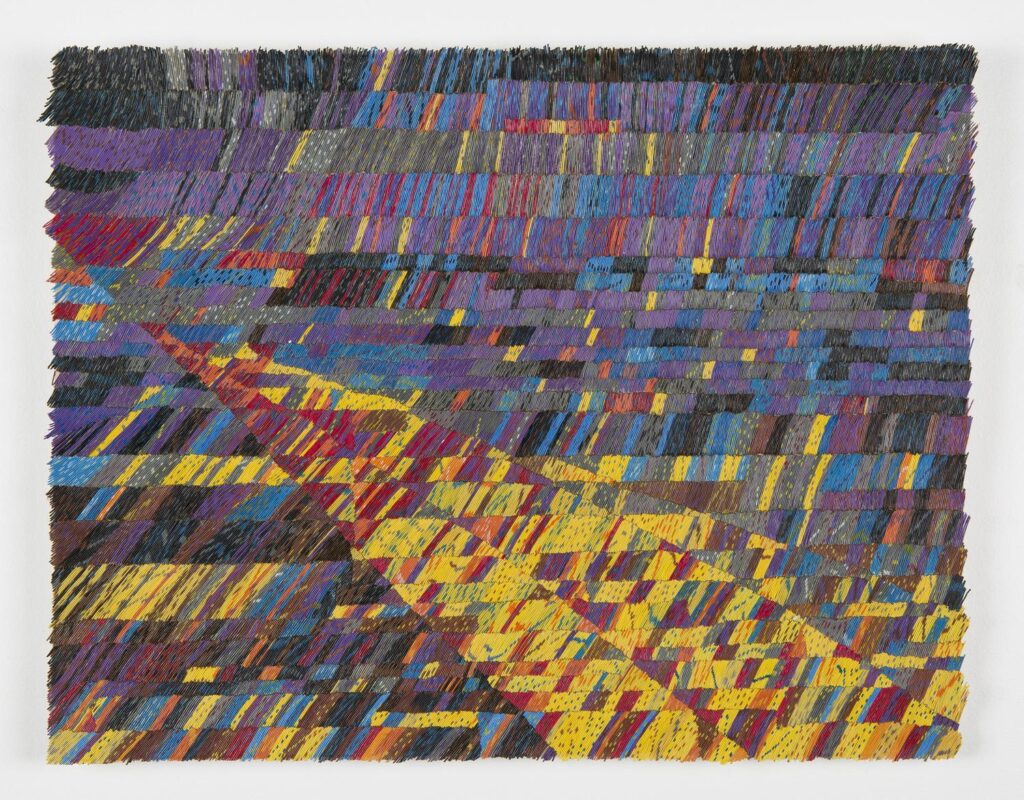 A wide, rectangular textile composed of multicoloured woven bands, crossed by a bold diagonal shape that cuts through the layered surface like a shifting path.