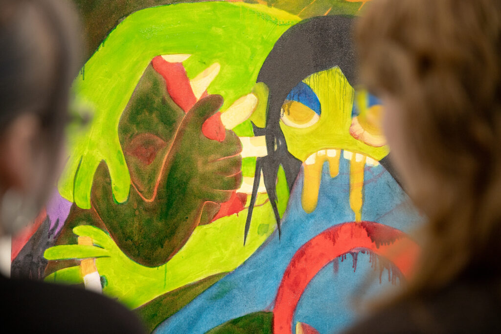 Visitors view a vivid painting featuring bold green and blue figures with dripping paint and expressive, surreal forms.
