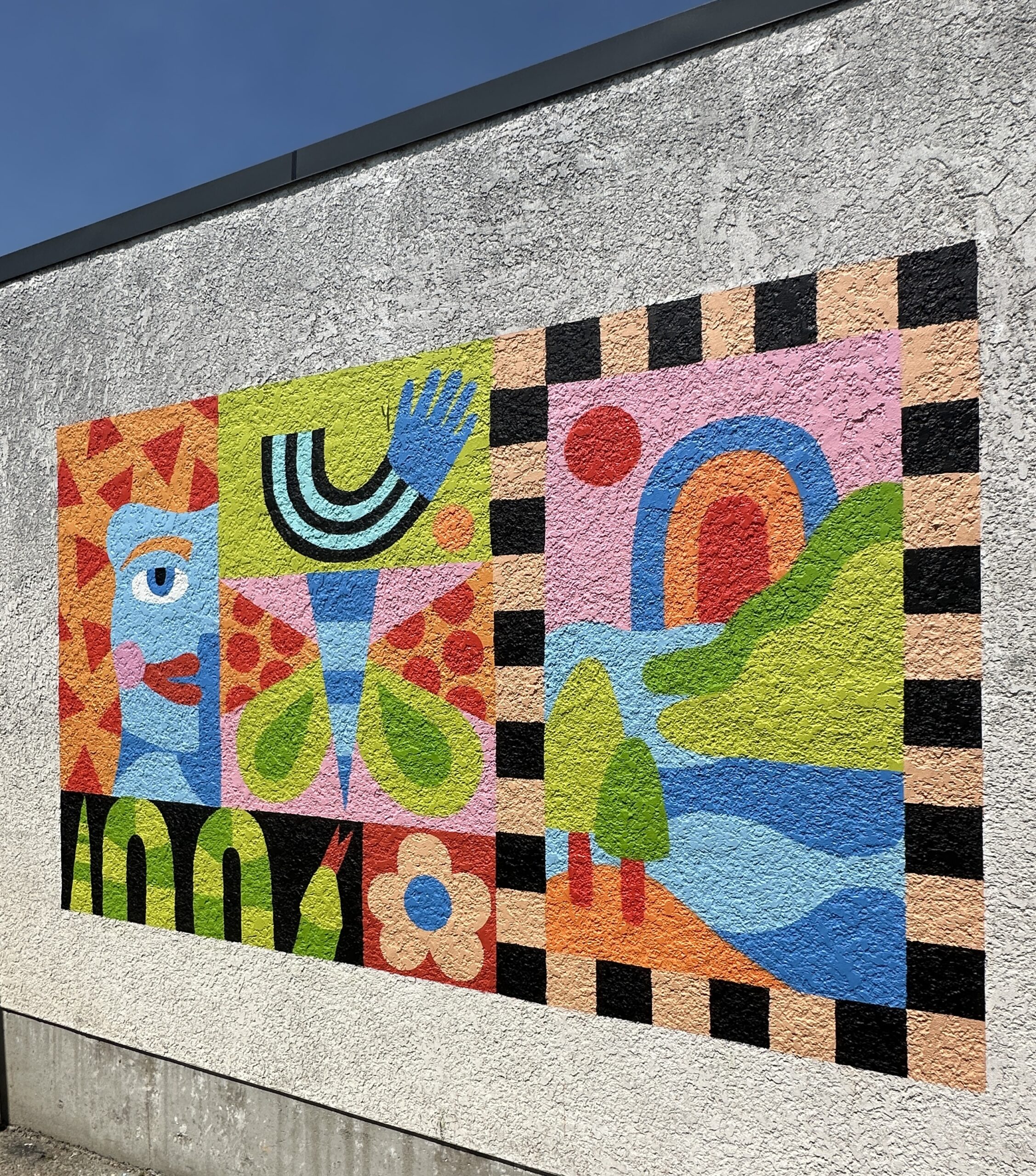 Outdoor geometric mural featuring stylized faces, hands, leaves and bold colour blocks.