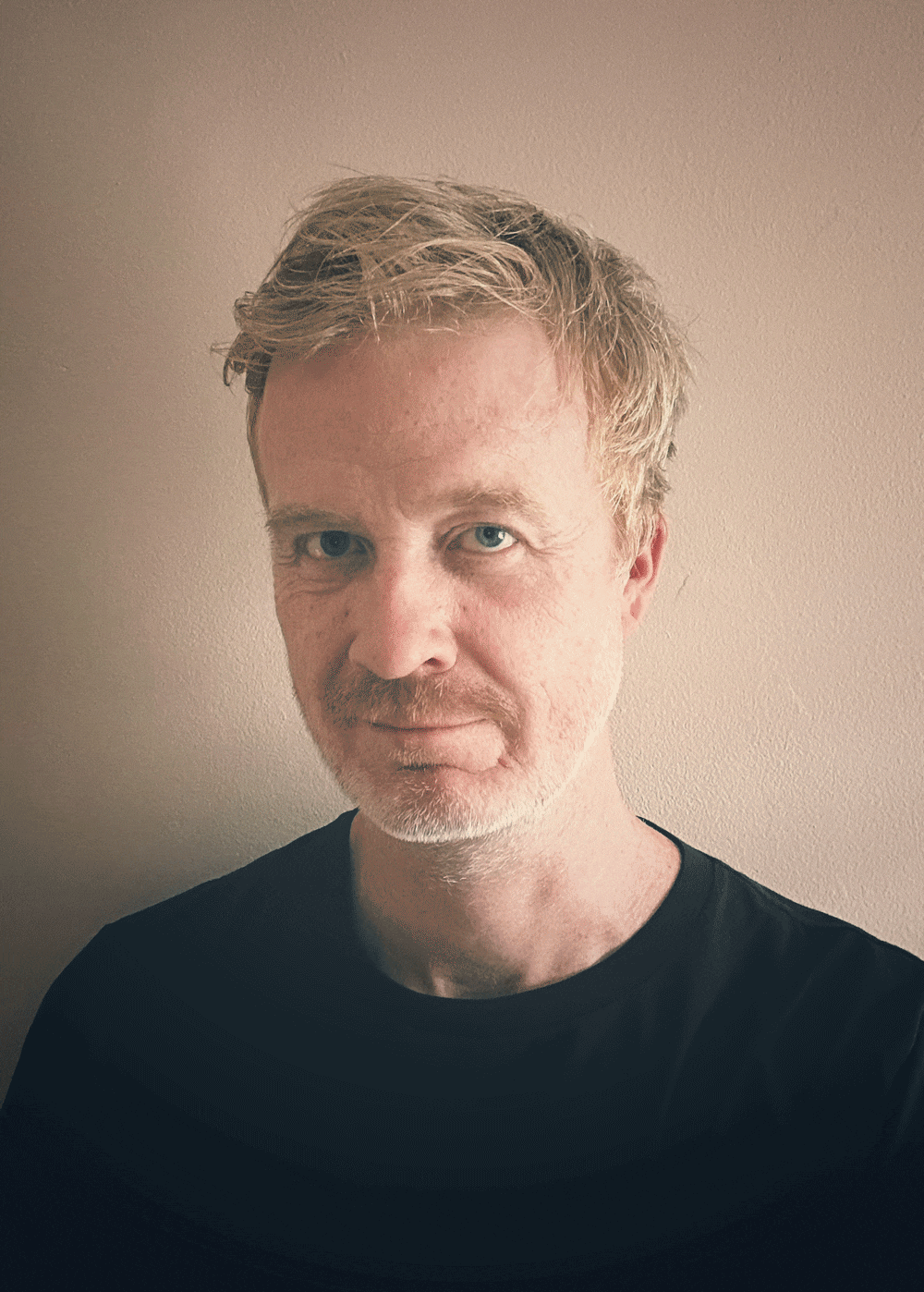 A close portrait of a person against a soft, neutral wall slowly disappears to reveal only the wall behind them.