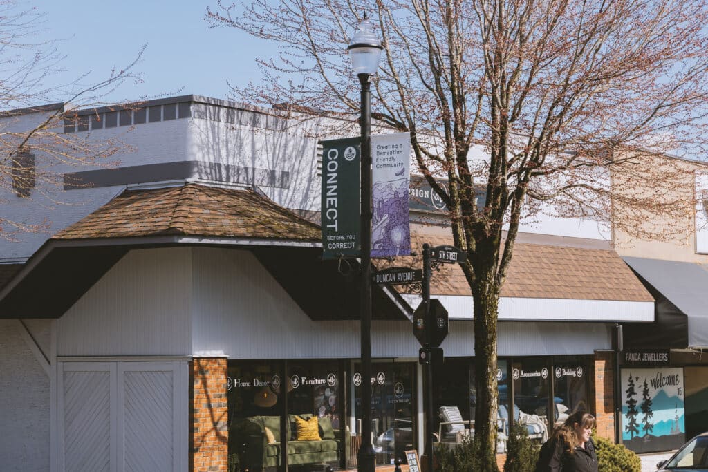A street banner hangs from a light post on a street corner in downtown Courtenay, BC.