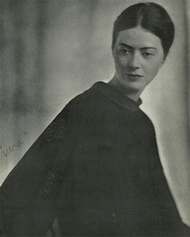 A black and white photo of a woman in a black long gown looking off to the side